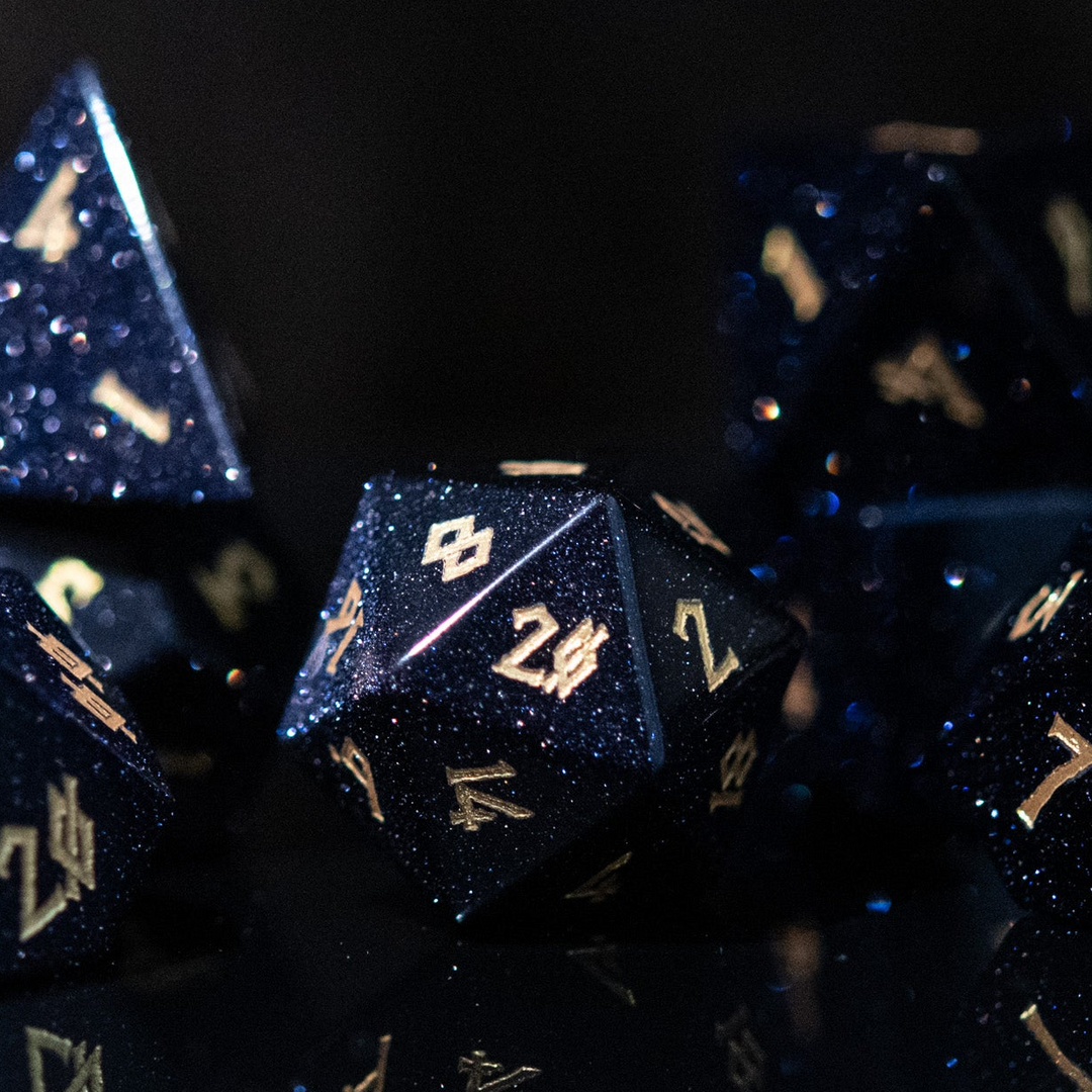 A set of hand-carved blue sandstone dice with gold numbers, reflecting a sparkling effect similar to stars.