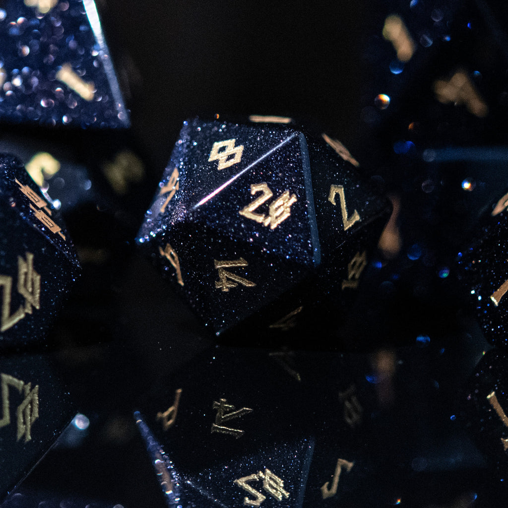 A set of hand-carved blue sandstone dice with gold numbers, reflecting a sparkling effect similar to stars.
