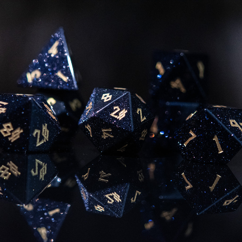 A set of hand-carved blue sandstone dice with gold numbers, reflecting a sparkling effect similar to stars.