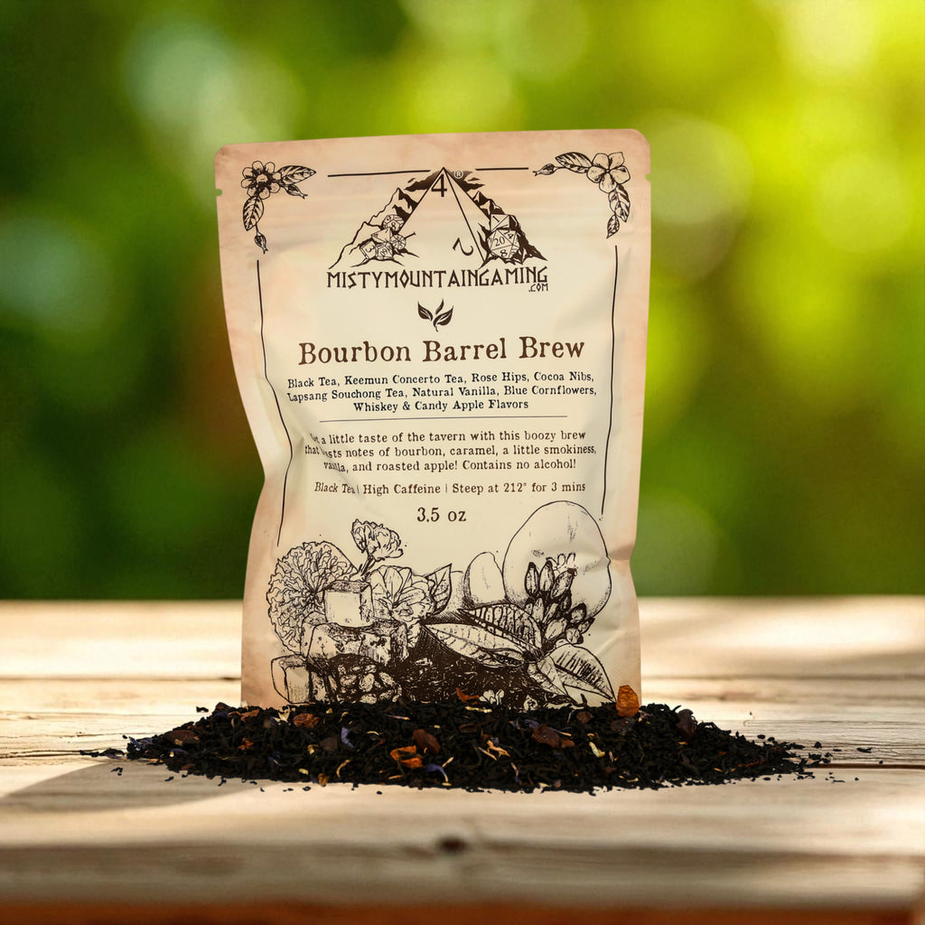 Tea bag labeled 'Bourbon Barrel Brew' from Misty Mountain Gaming Tea on a wooden surface with a blurred green background.