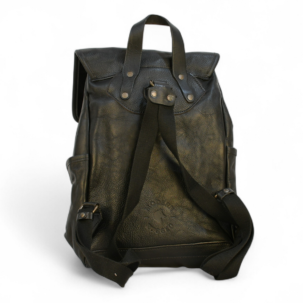 black modern rugged leather backpack on a wooden table with books and a globe in the background