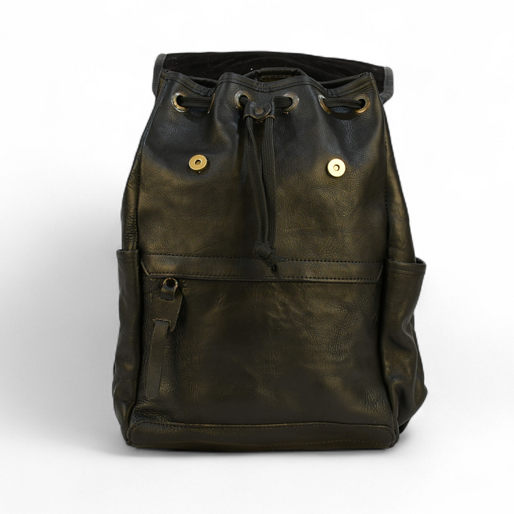 black modern rugged leather backpack on a wooden table with books and a globe in the background