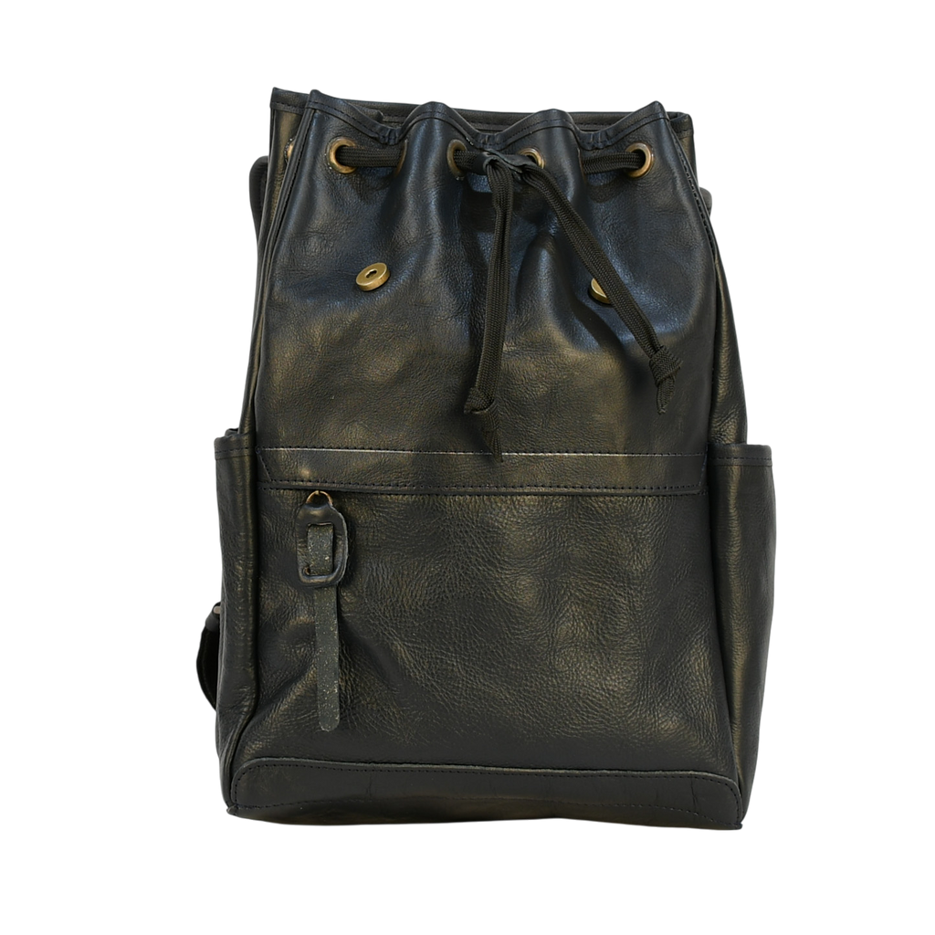 Dark leather navy modern rugged backpack on a wooden surface with books in the background