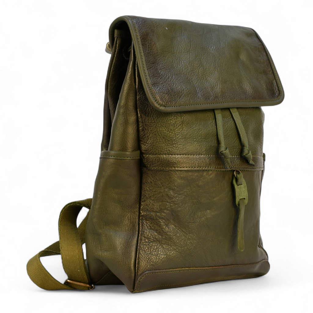 Green modern rugged leather backpack on a wooden table with a blurred indoor background