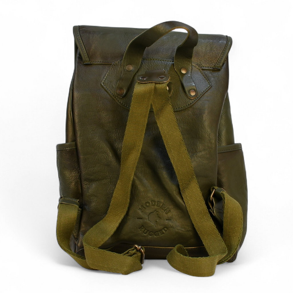 Green modern rugged leather backpack on a wooden table with a blurred indoor background
