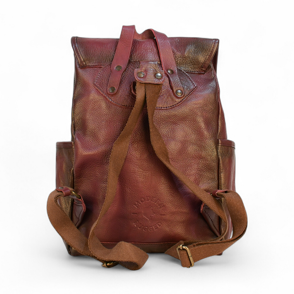 Purple modern rugged leather backpack on a rocky outcrop with a mountainous landscape and sunset in the background