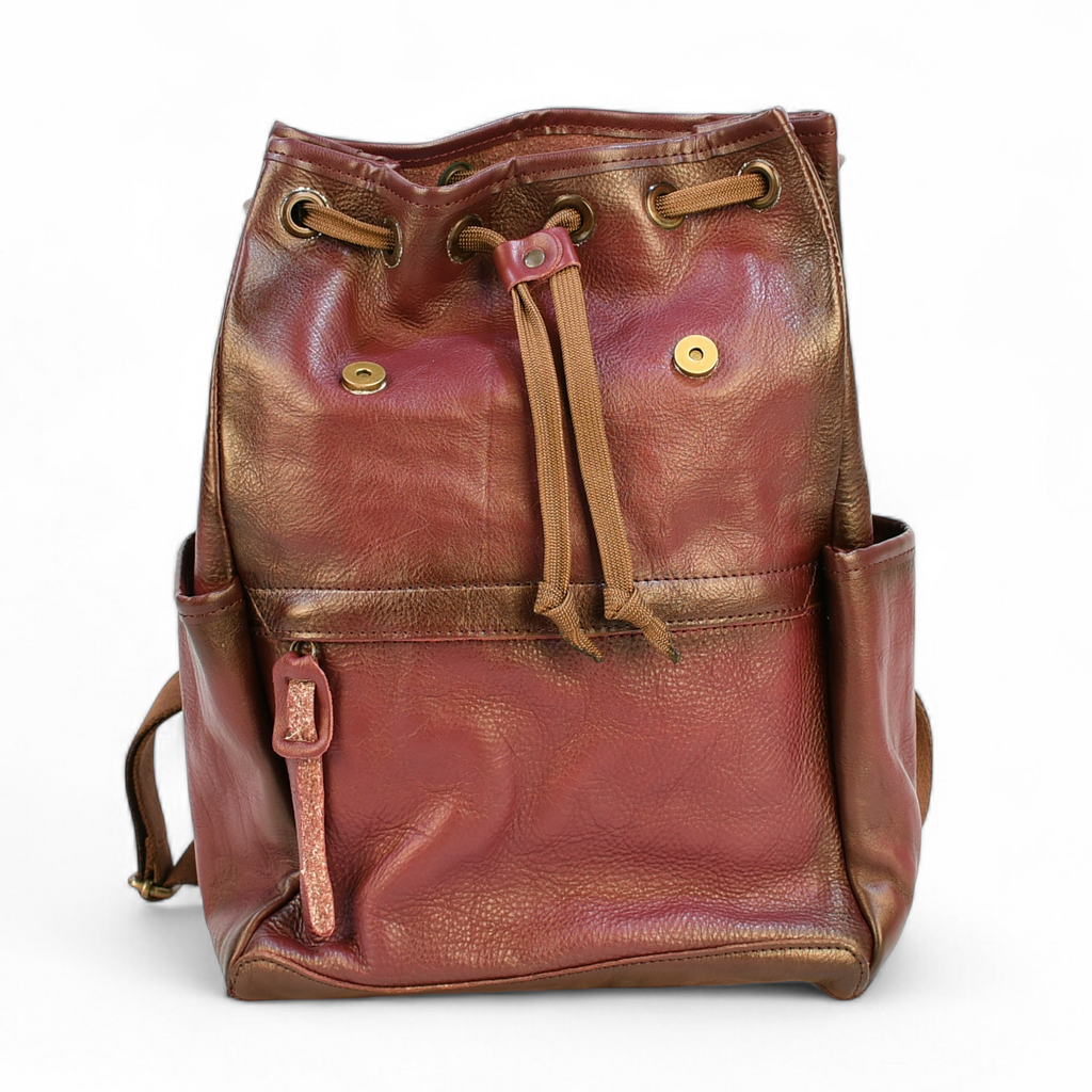 Purple modern rugged leather backpack on a rocky outcrop with a mountainous landscape and sunset in the background