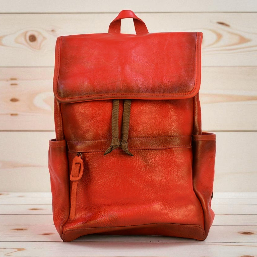Red modern rugged leather backpack on a wooden surface