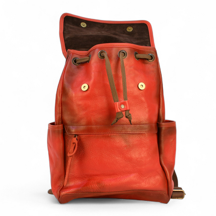 Red modern rugged leather backpack on a wooden surface