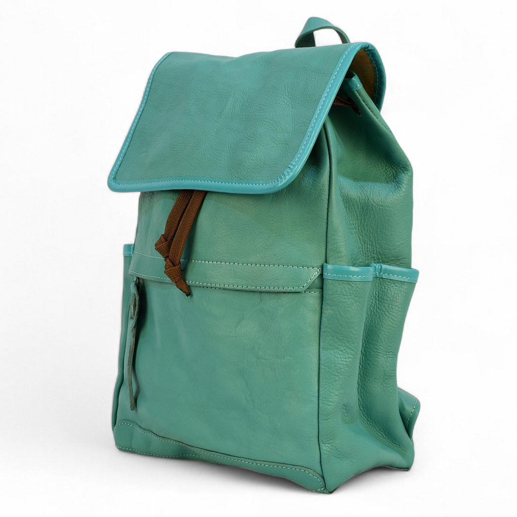 Teal modern rugged leather backpack with brown straps on a wooden surface