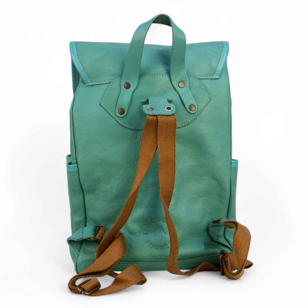 Teal modern rugged leather backpack with brown straps on a wooden surface