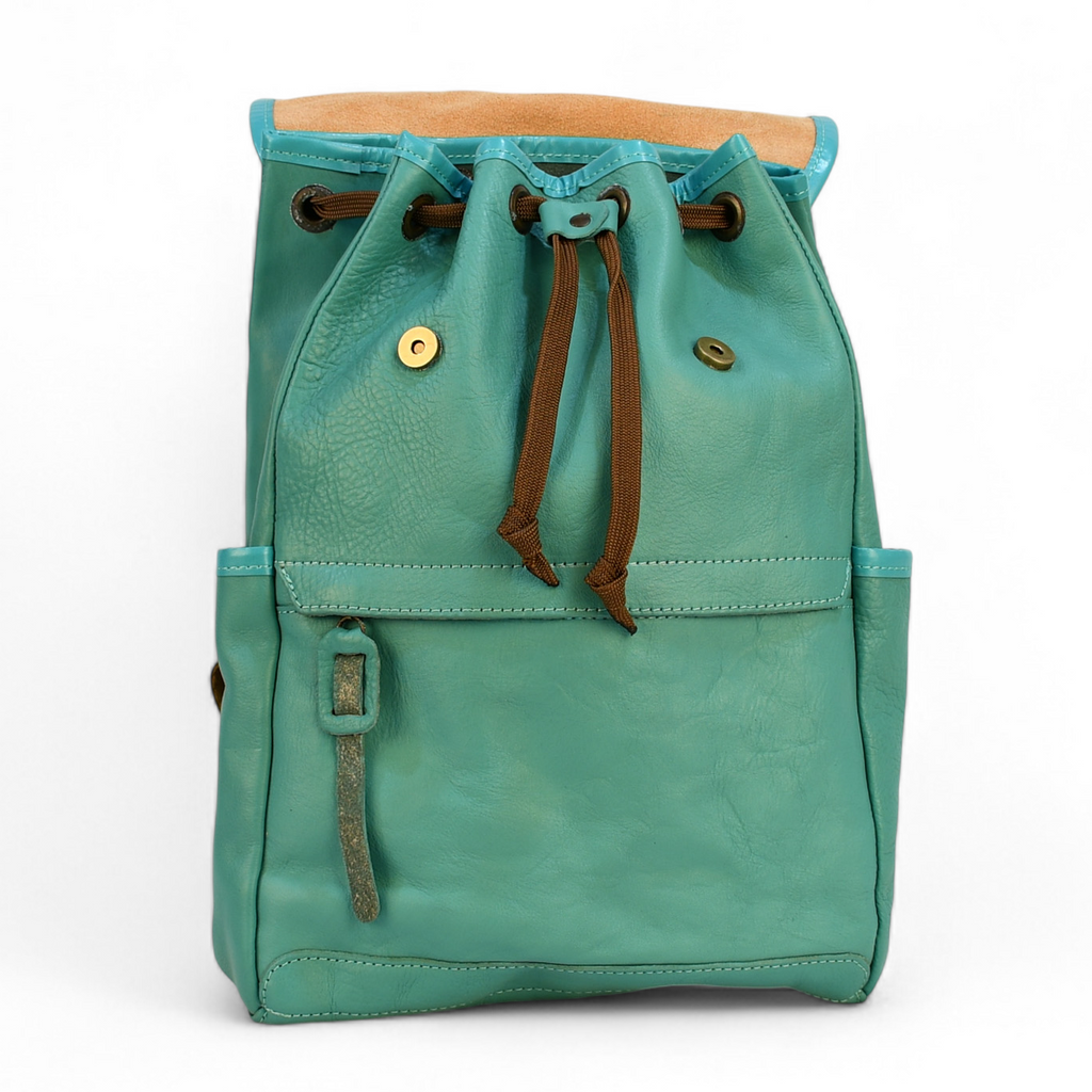 Teal modern rugged leather backpack with brown straps on a wooden surface