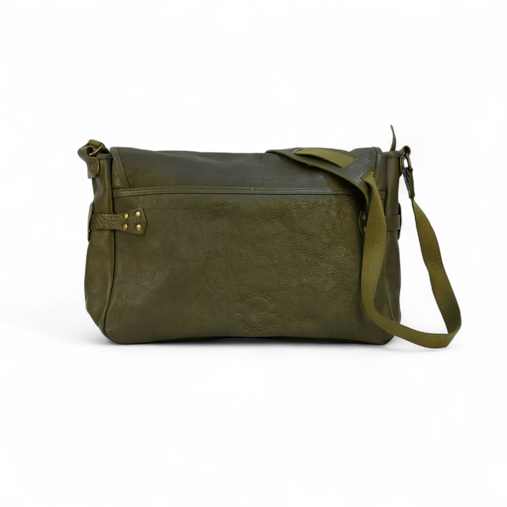 Green modern rugged messenger leather bag on a wooden surface with a vintage bookshelf background