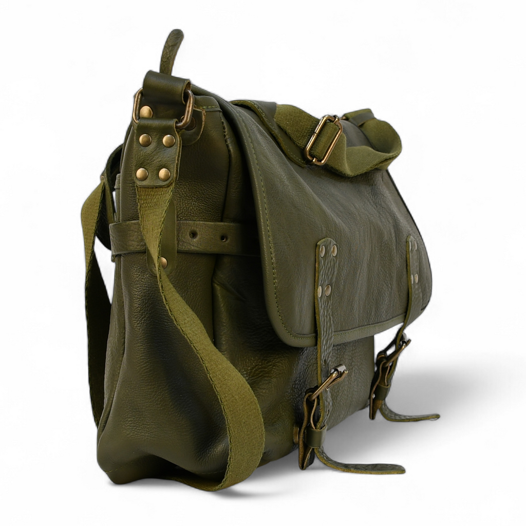 Green modern rugged messenger leather bag on a wooden surface with a vintage bookshelf background