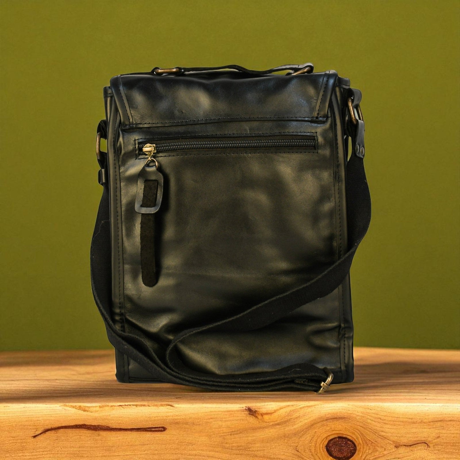 Black leather bag on a wooden surface with a green background