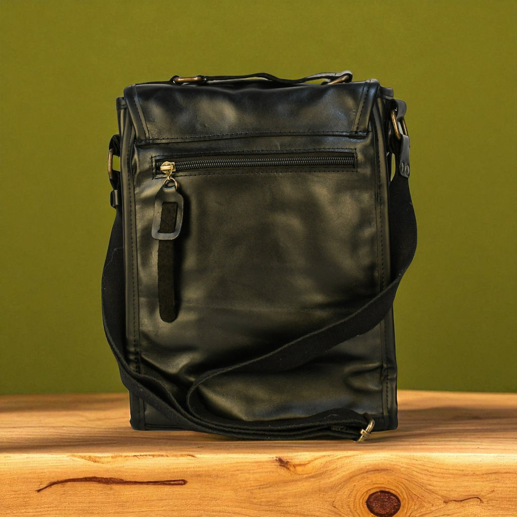 Black leather bag on a wooden surface with a green background
