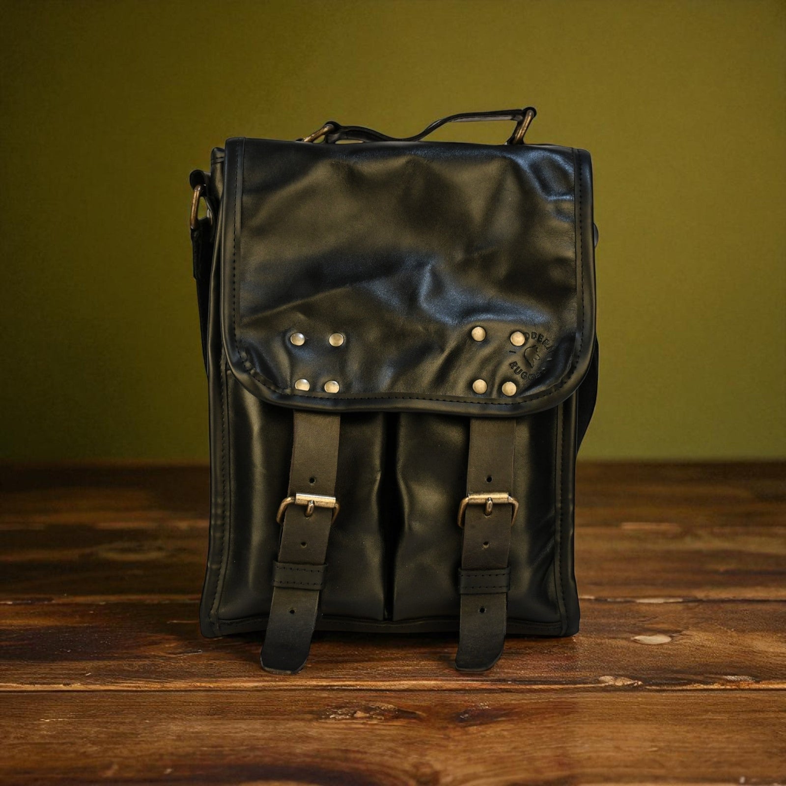 Black leather backpack with studs on a wooden surface and green background