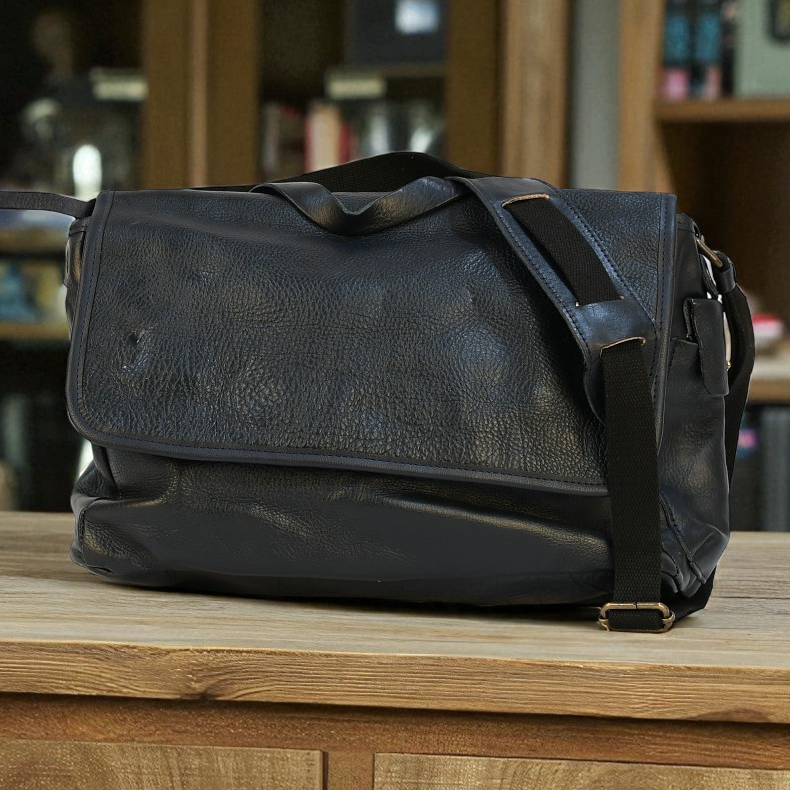 modern rugged black leather bag with a black strap on a stone pavement
