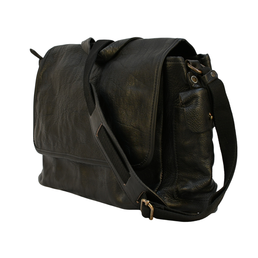 modern rugged black leather bag with a black strap on a stone pavement