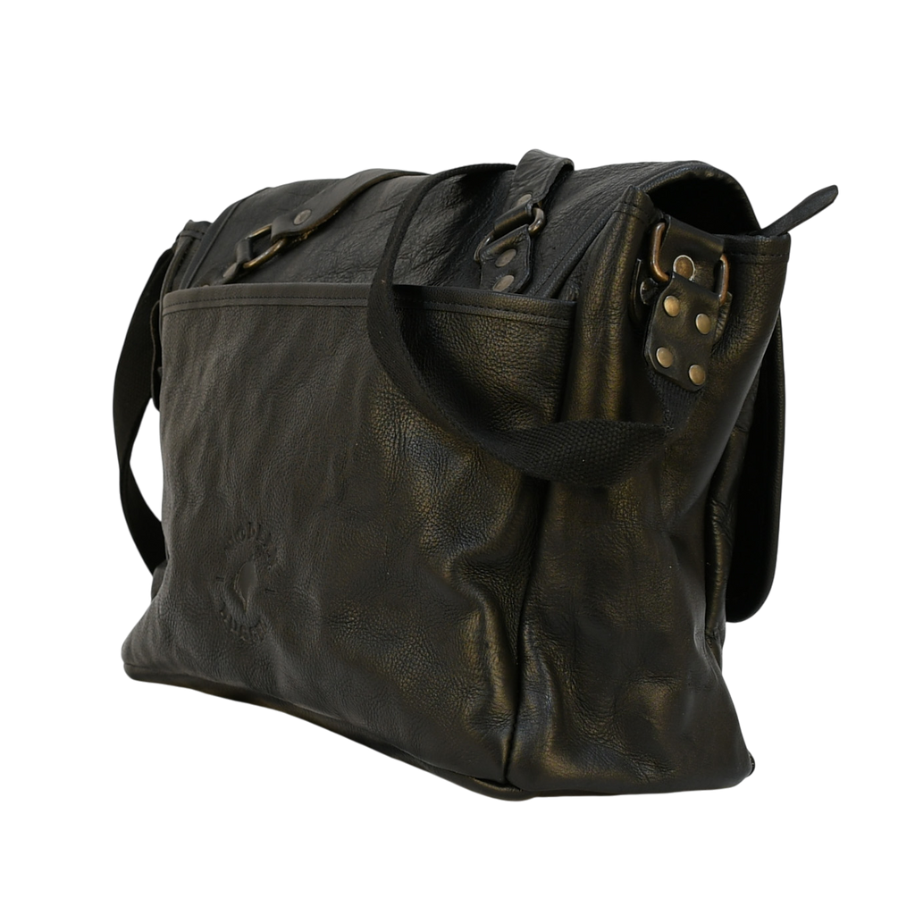 modern rugged black leather bag with a black strap on a stone pavement