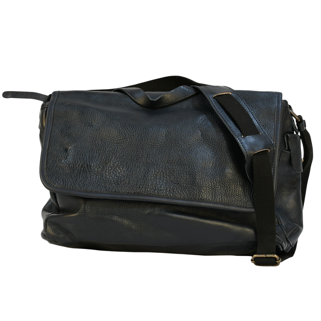 Navy leather modern rugged messenger bag on a wooden table with a gray background