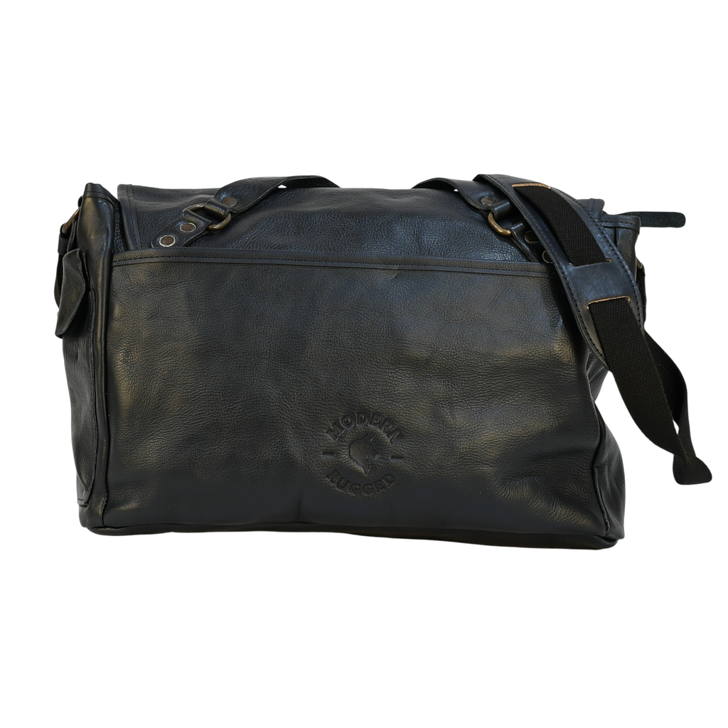 Navy leather modern rugged messenger bag on a wooden table with a gray background