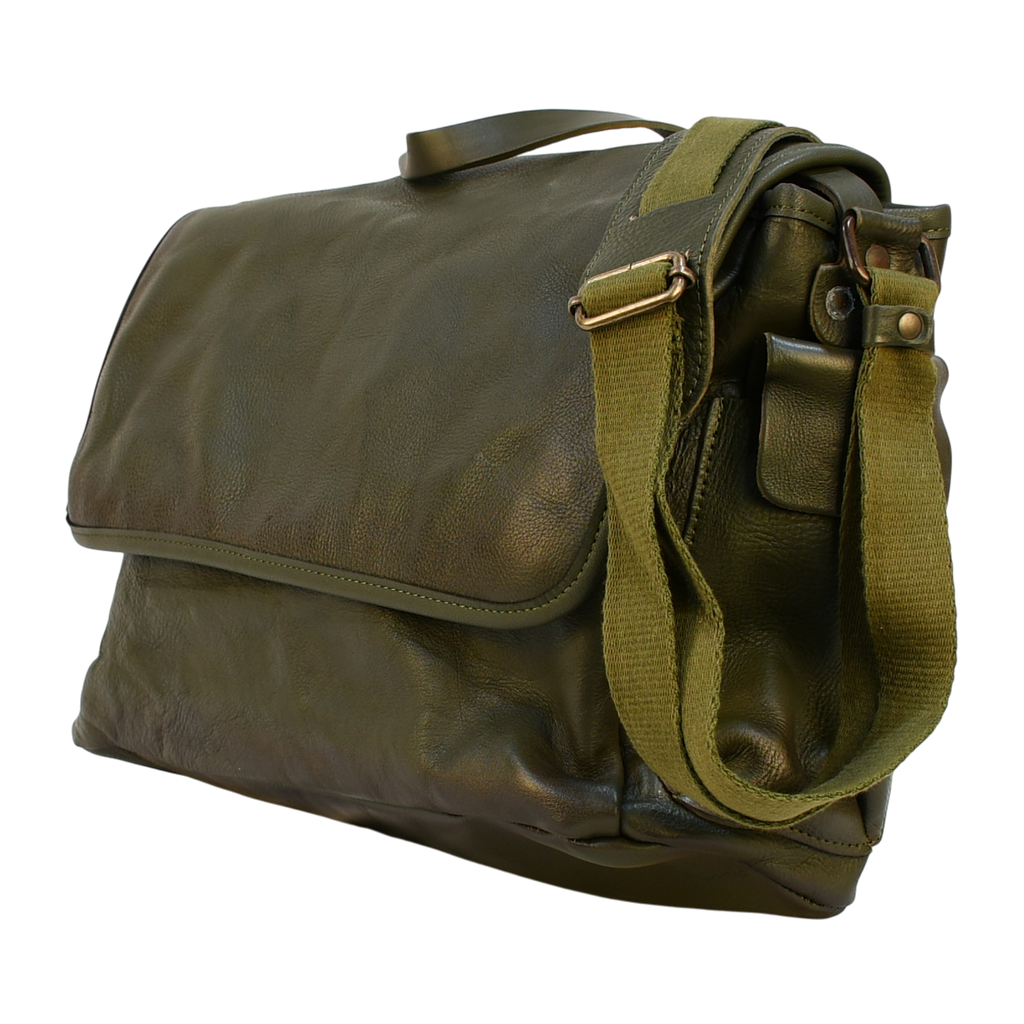 Green modern rugged leather bag on a wooden desk with bookshelves and a window in the background