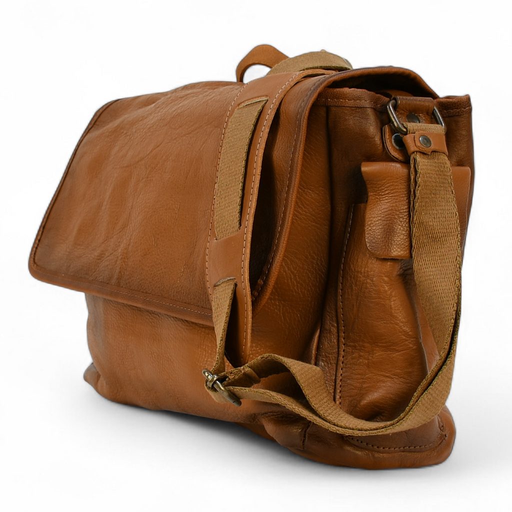 Brown leather modern rugged messenger bag on a surface with a window in the background