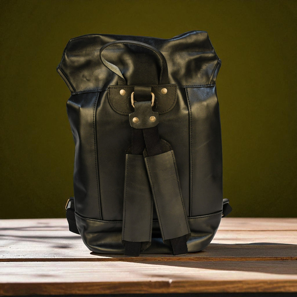 Black leather backpack on a wooden surface with a green background