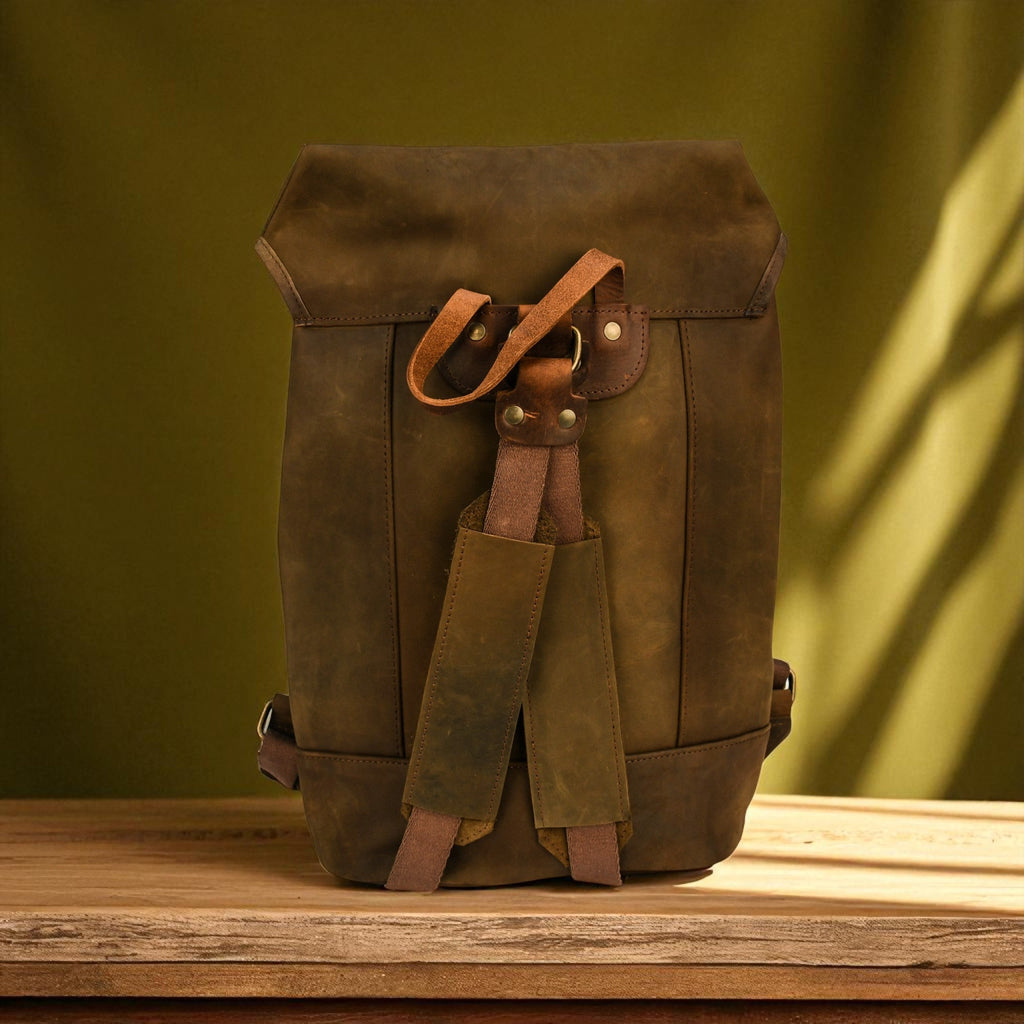 Brown leather backpack on a wooden surface with a green background