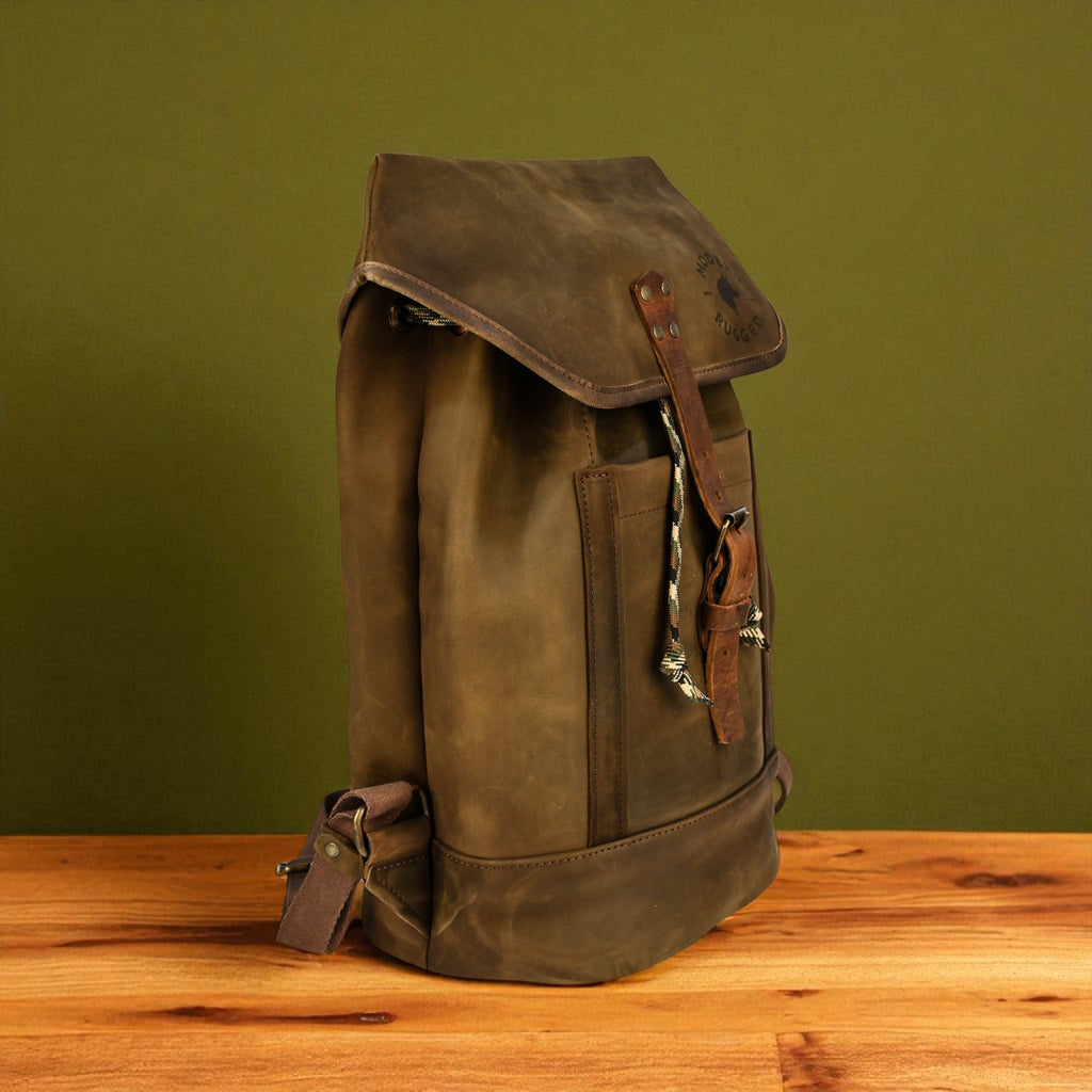 Brown leather backpack on a wooden surface with a green background
