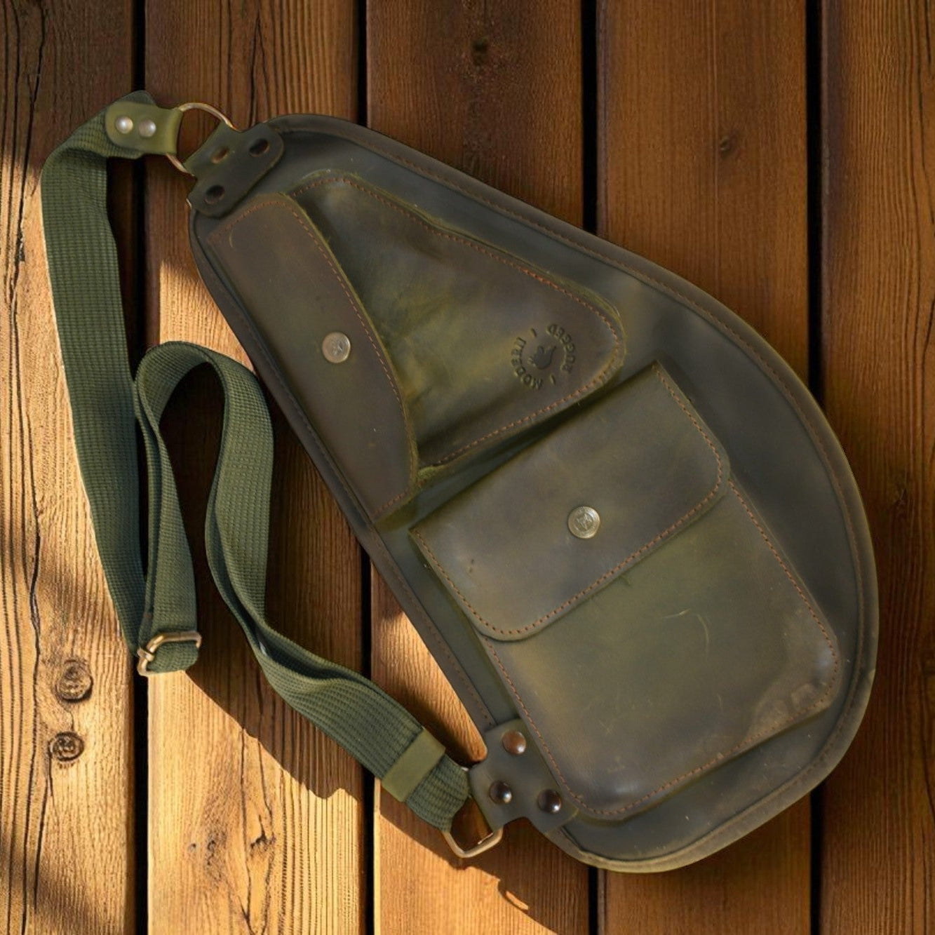 Green leather bag with a strap on a wooden surface