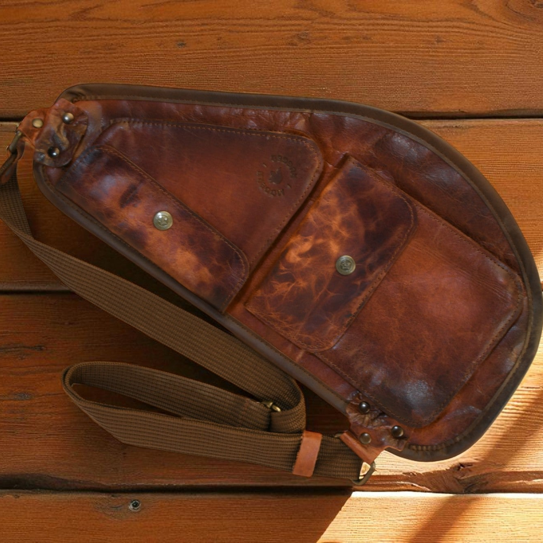 Brown leather bag with a strap on a wooden surface
