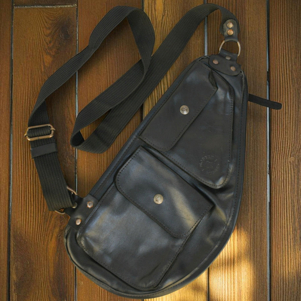 Black leather bag with a strap on a wooden surface