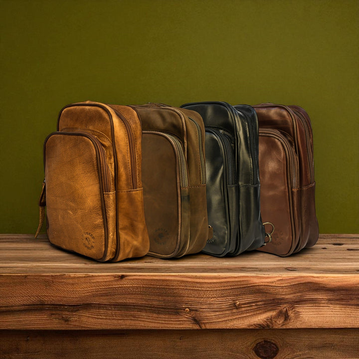 Four leather bags in various colors on a wooden surface with a green background
