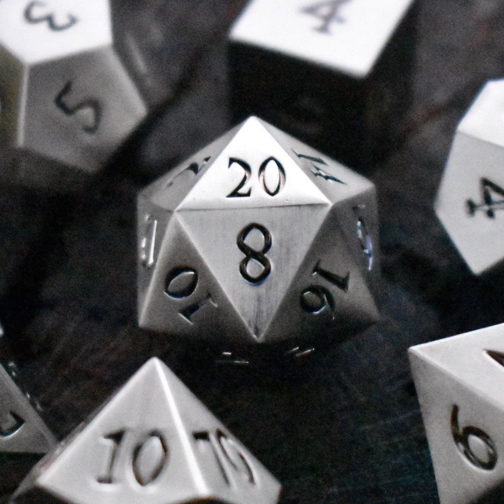 A collection of silver metal dice with engraved numbers, including various shapes such as a d4, d6, d8, d10, d12, and d20.