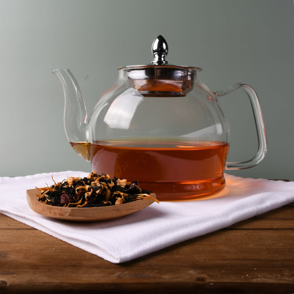 loose tea leaves beside a glass tea pot