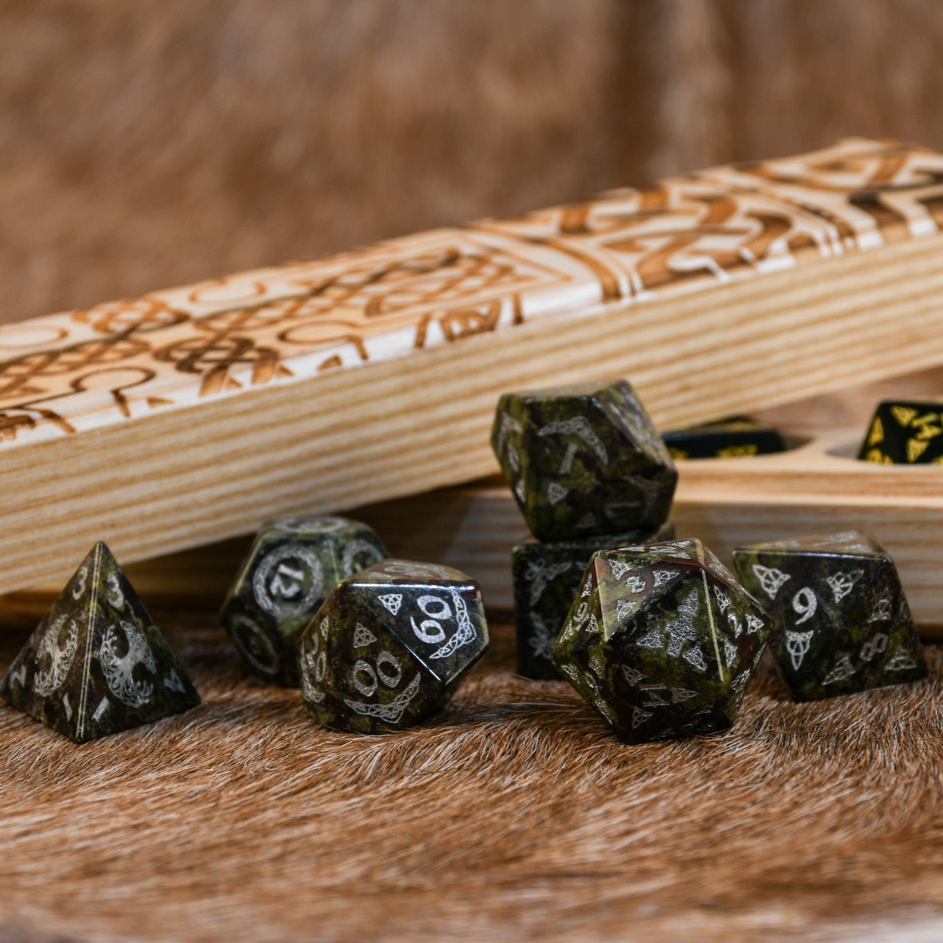 A set of hand-carved Celtic Dragon Blood Jasper Stone Dice with engraved numbers, displayed on a tartan surface with Celtic knot patterns.