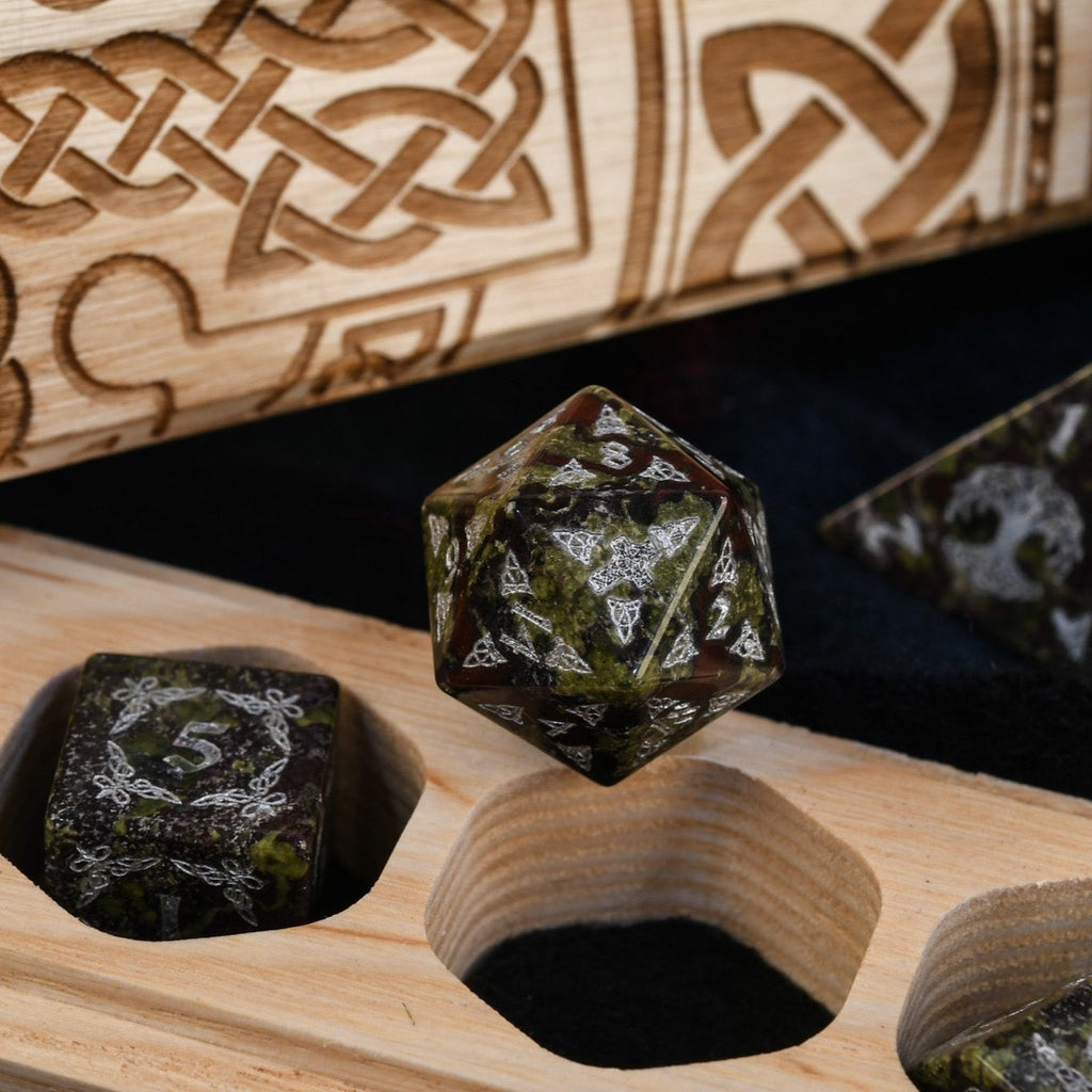 A set of hand-carved Celtic Dragon Blood Jasper Stone Dice with engraved numbers in a dnd dice vault engraved with celtic knots