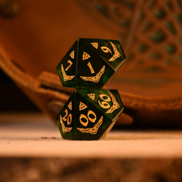 a set of polyhedral Celtic Green Glass Dice with golden numbering and celtic designs