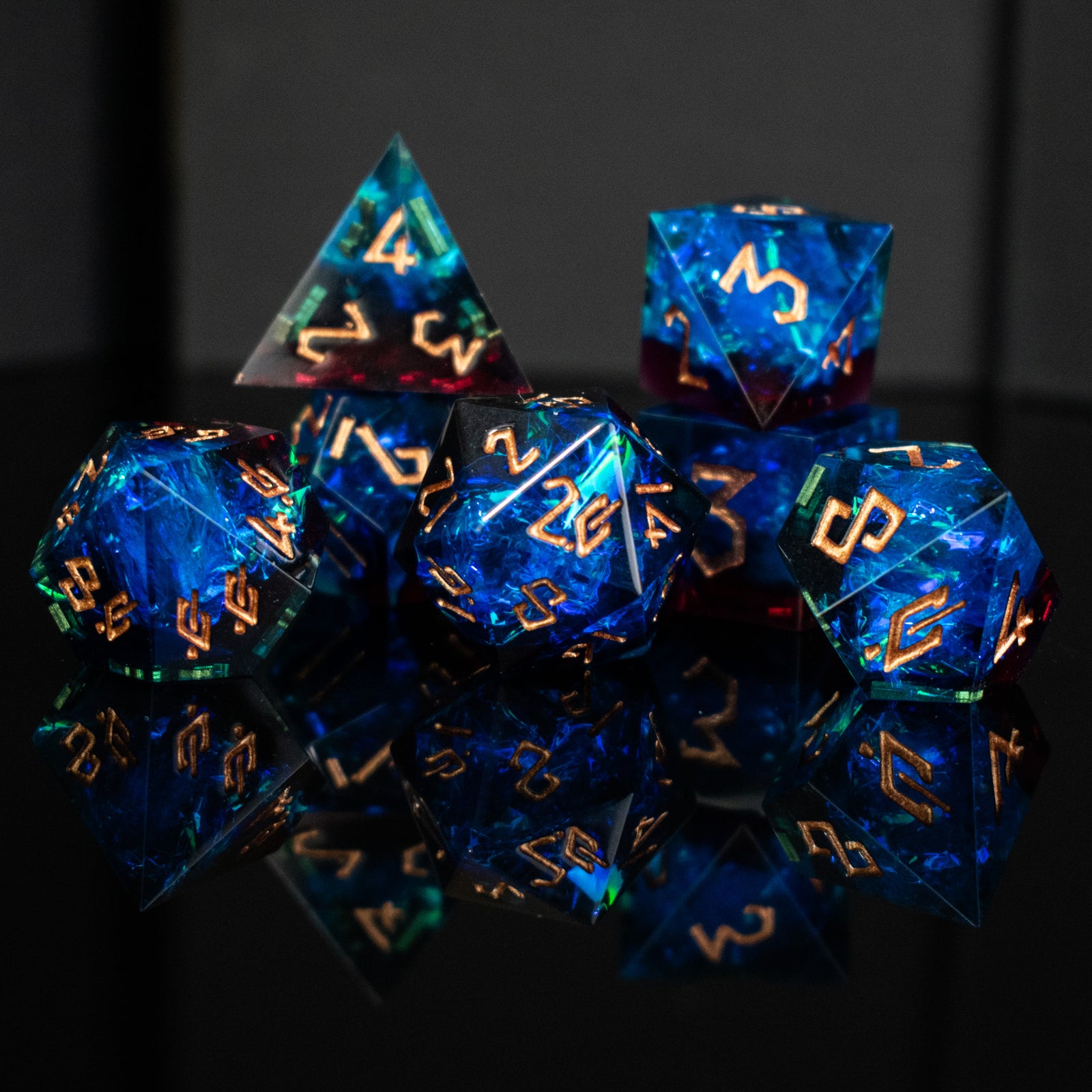 A set of sharp-edged, multicolored resin dnd dice with gold engraved numbers, reflecting on a surface.