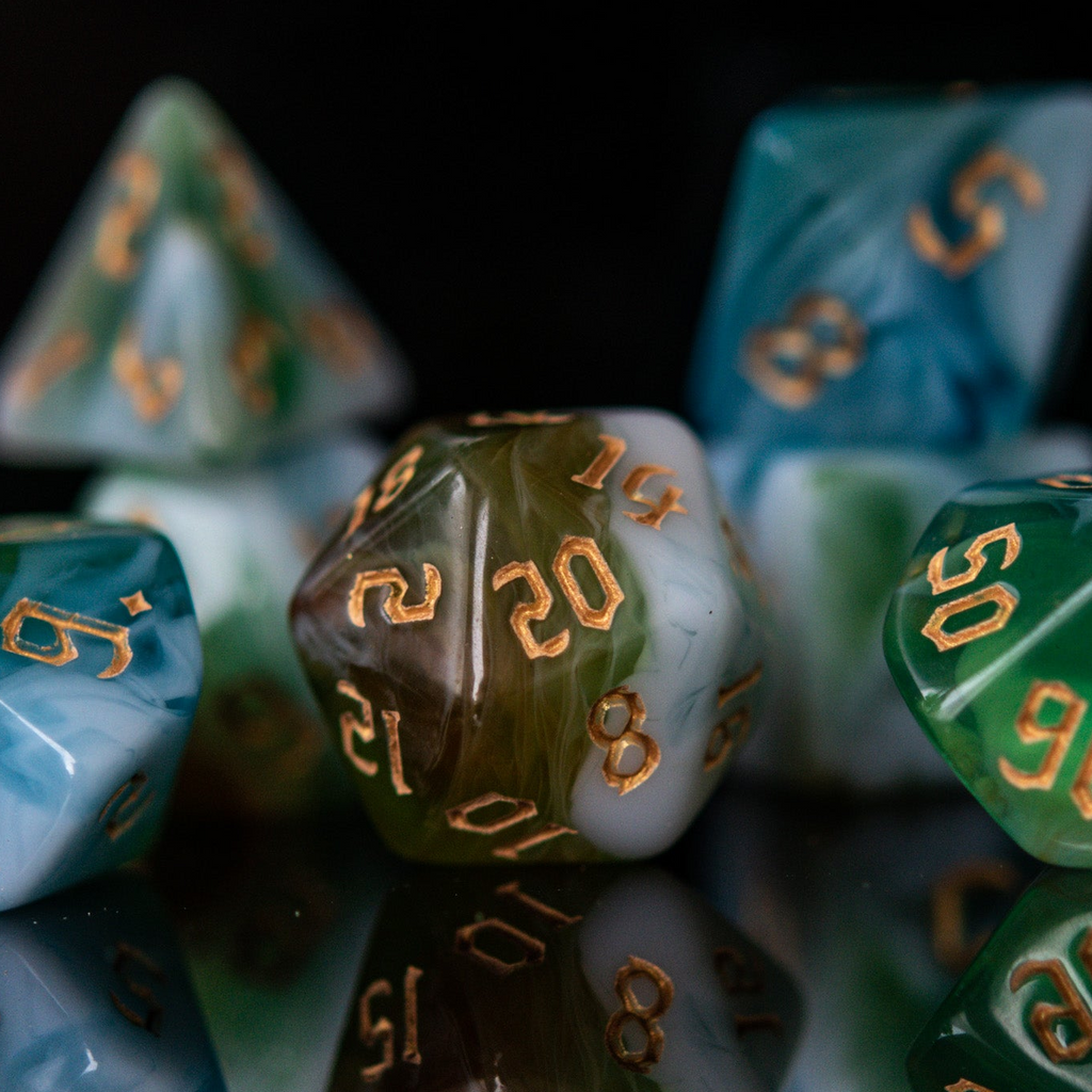Close-up of polyhedral dice with green and blue colors on a reflective surface.