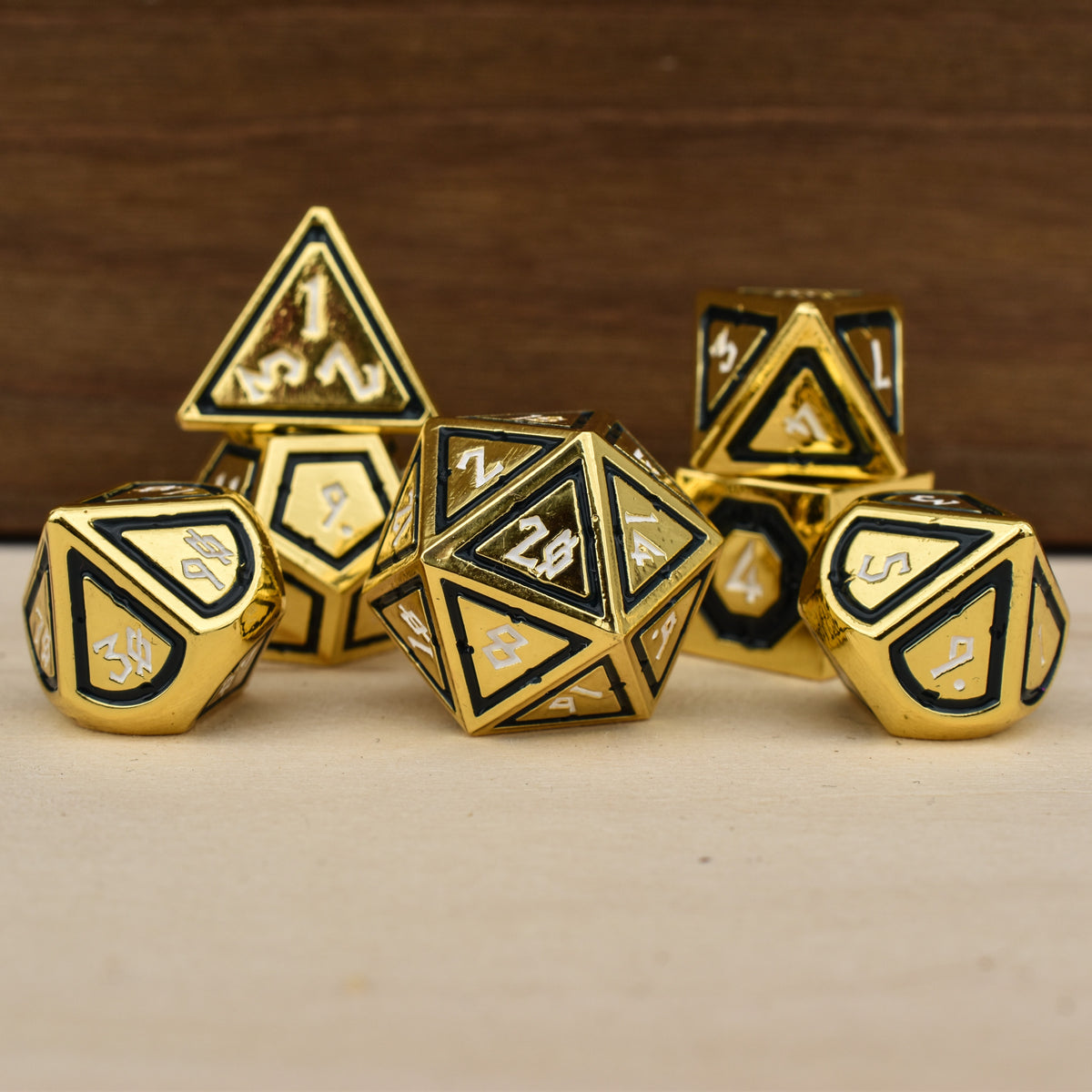 A set of gold polyhedral metal dnd dice with black borders on each face and white numbering