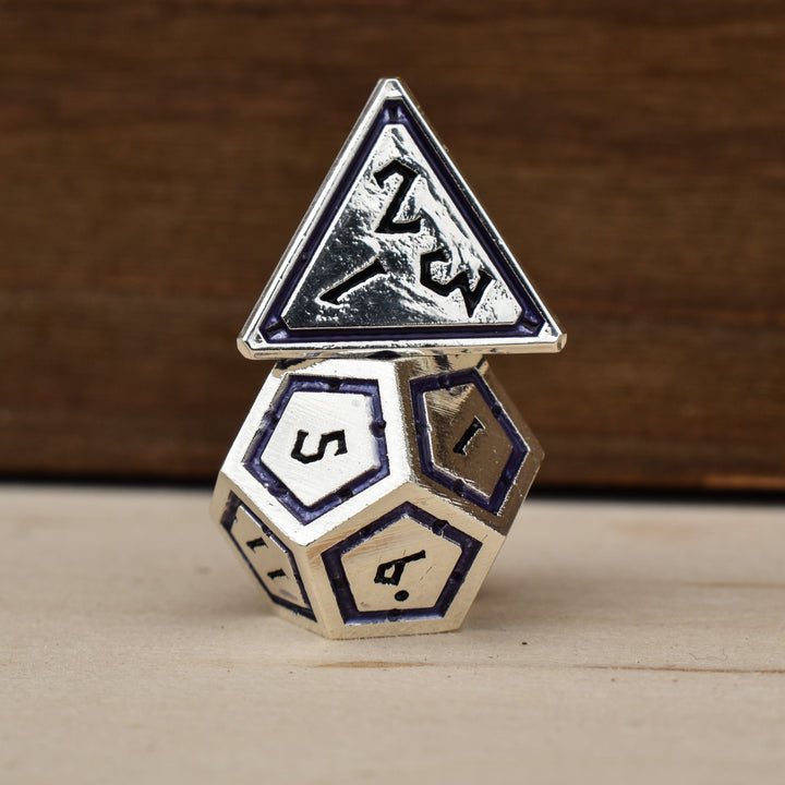 A set of silver polyhedral metal dnd dice with deep purple borders on each face and black numbering
