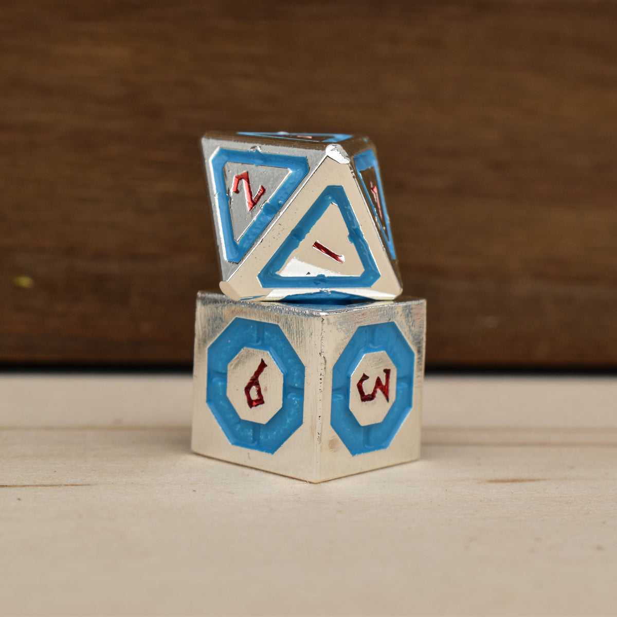 silver polyhedral metal dnd dice with blue borders on each face and red numbering
