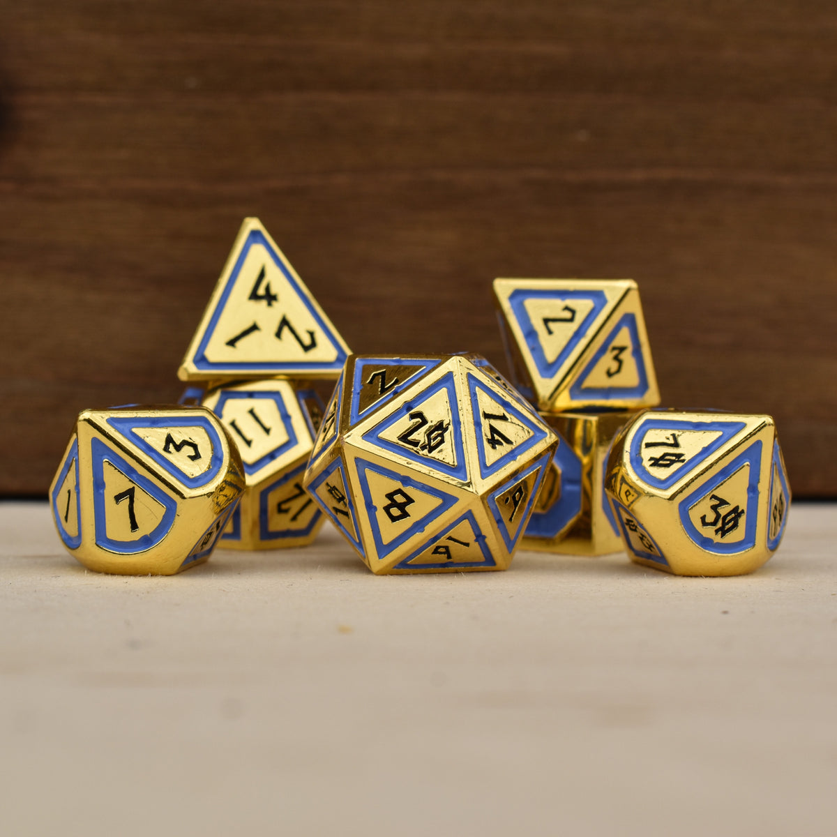 A set of gold polyhedral dnd dice with blue borders on each face and black numbering
