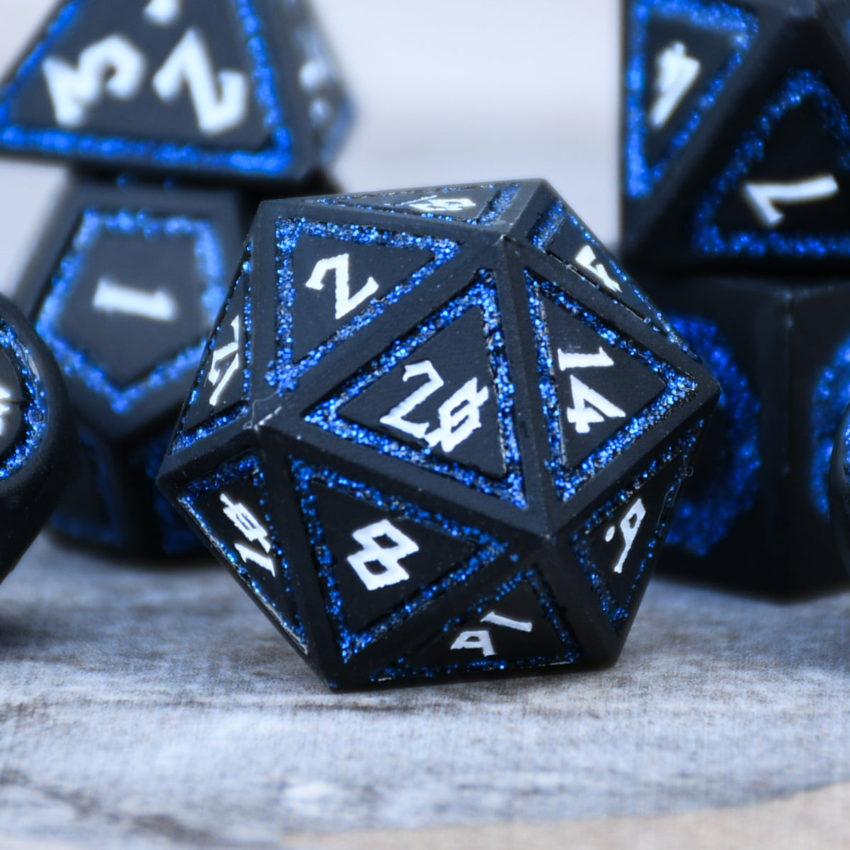 black metal d20 die with white numbering and blue dark glitter border on each face