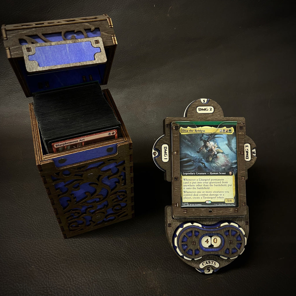 A wooden deck box with intricate cut-out patterns, featuring a purple interior, accompanied by a command plate and game tokens.