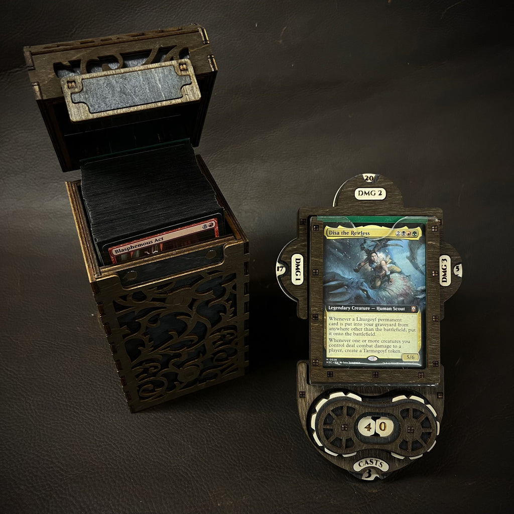 A wooden deck box with intricate cut-out patterns, featuring a purple interior, accompanied by a command plate and game tokens.