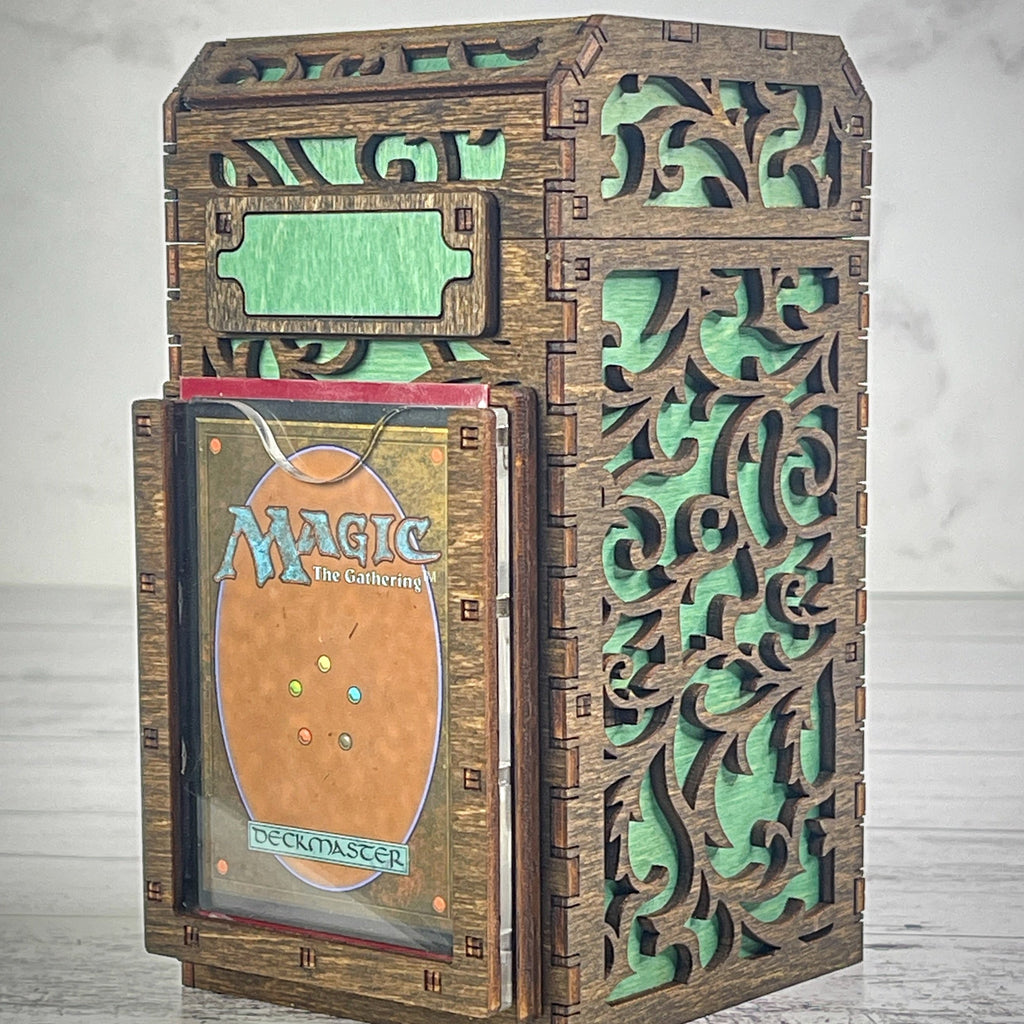 A wooden deck box with a intricate carved design, featuring a removable magnetic plate on the front for holding cards from the game 'Magic: The Gathering'.